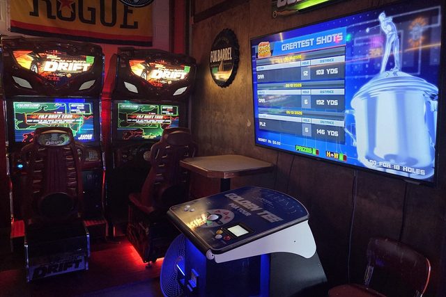 A Golden Tee PGA Tour cabinet on the big screen next to two sit-down Fast and Furious Drift racers
