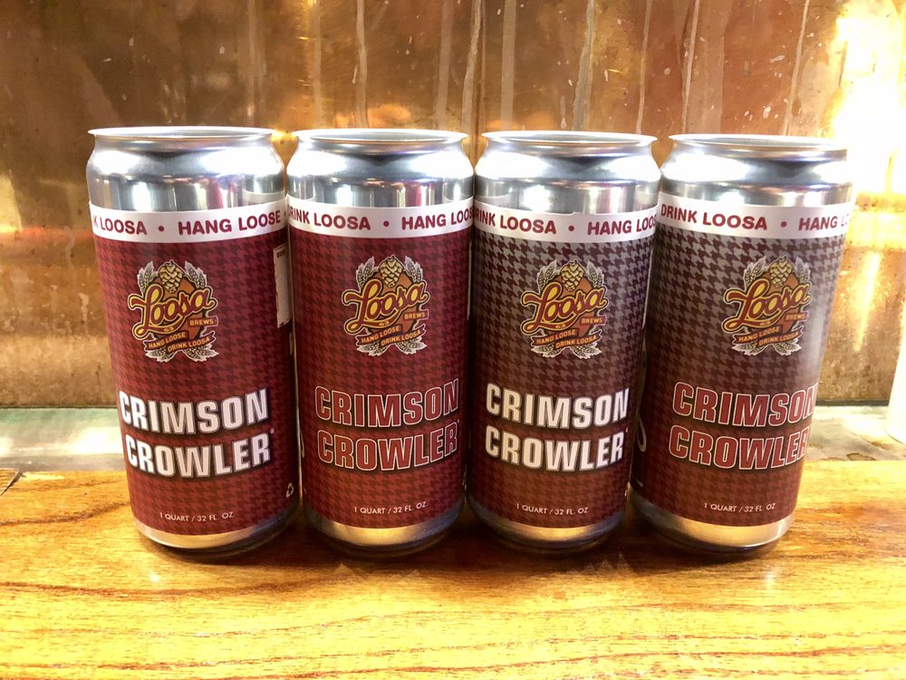Four sealed Crimson Crowler cans lined up on the bar in front of the tap wall