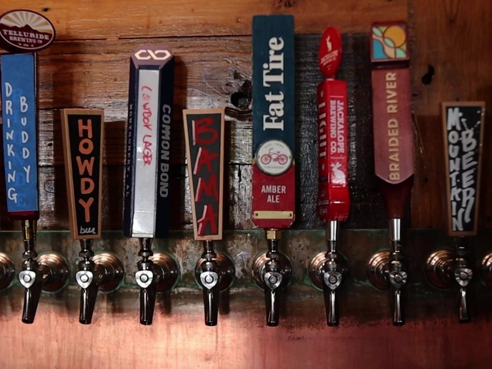 A run of Loosa Brews tap handles on the reclaimed-wood wall — Avondale, Porch Light, Innertube, Drinking Buddy, Howdy, Common Bond, Bama, Fat Tire, Jackalope, Braided River