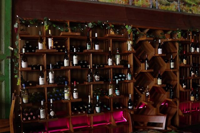 Loosa Brews' wine wall — floor-to-ceiling wooden racks of bottles strung with vine garland and fairy lights